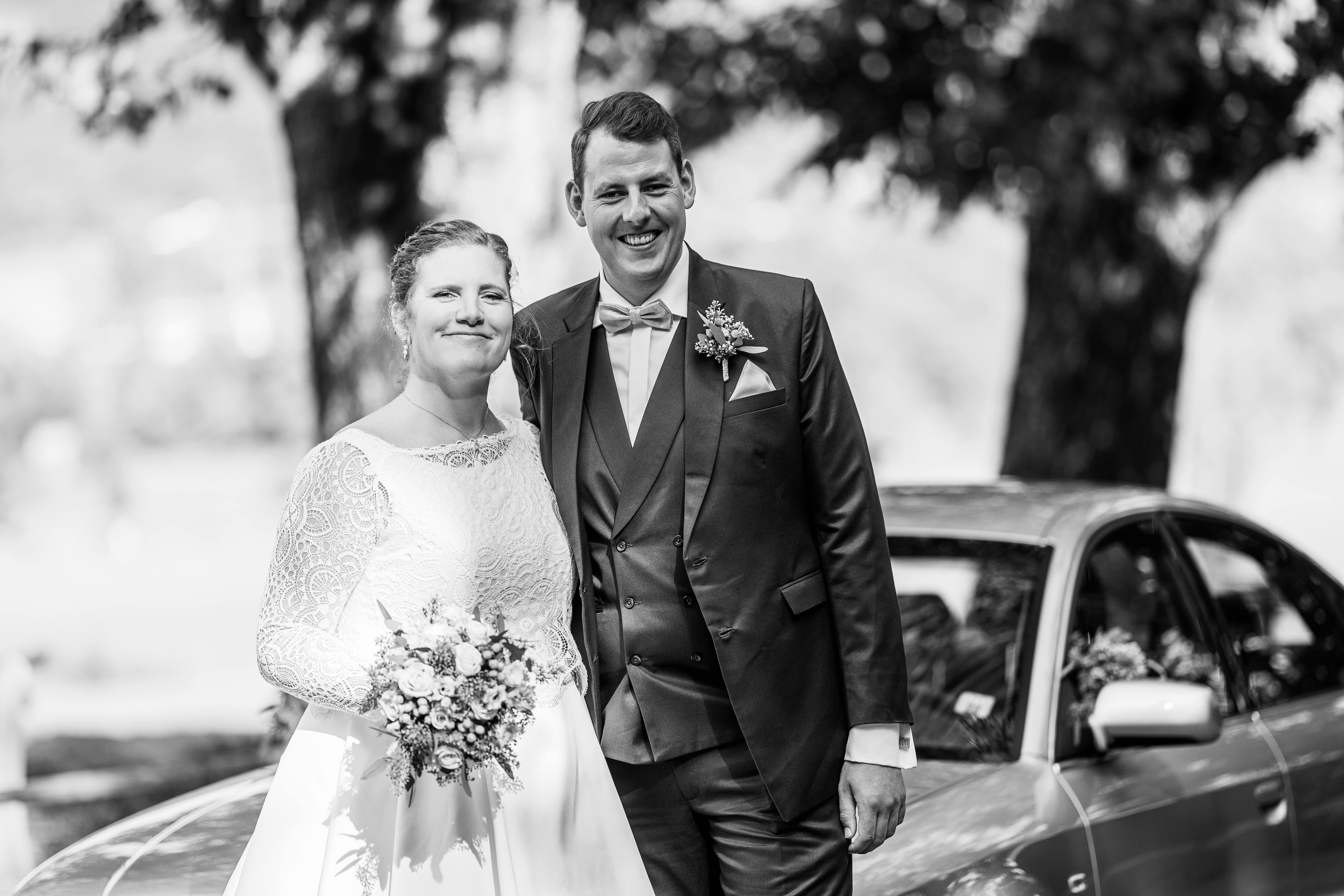 Brautpaar vor Hochzeitsauto